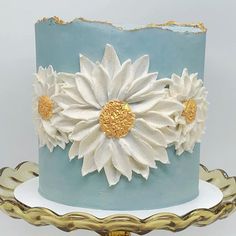 a blue cake with white and gold flowers on it