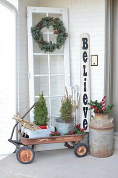 a wheelbarrow filled with potted plants next to a sign that says believe