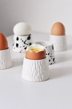 three ceramic eggs with black spots and an egg yolk in the middle on a white surface