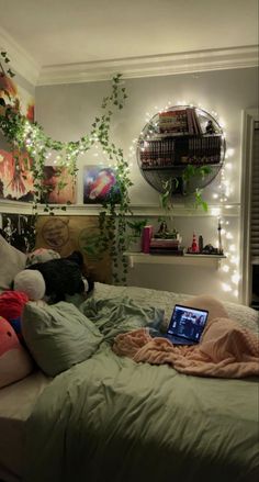 a laptop computer sitting on top of a bed in a bedroom with plants and lights