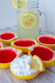 lemons with whipped cream sit on a wooden table next to a jar of lemonade