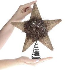 a person holding up a star decoration made out of burlock and rope with their hands