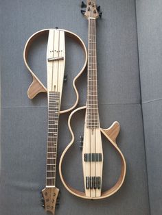 two wooden guitars sitting on top of a gray couch next to each other and one is made out of wood