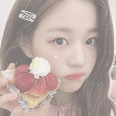 a girl holding up a pastry with strawberries on it