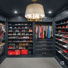 a walk in closet with lots of shoes and other items on the shelves, along with a chandelier