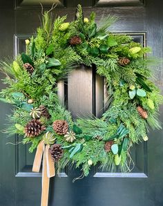 evergreen winter wreath with dried limes and pine cones on the front door for christmas