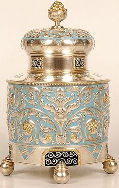 a blue and gold vase sitting on top of a white table next to a bell