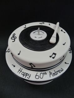 two white cakes with black and white music notes on the top one has a fork