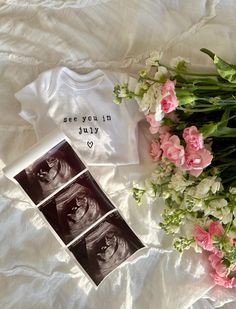 flowers and t - shirt laying on top of a bed next to a bouquet of pink carnations