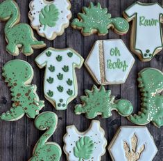 decorated cookies with green and white frosting are arranged on a wooden surface, including ones that say one baby