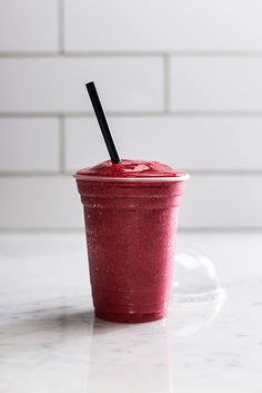 a smoothie in a plastic cup with a black straw sticking out of the top