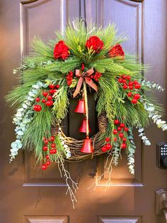 a christmas wreath hanging on the front door with bells and evergreen leaves, red roses and holly