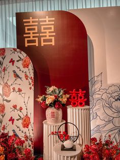 two vases with flowers are on display in front of a red and white wall