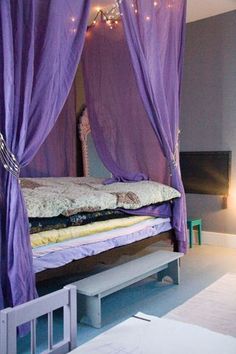 a purple canopy bed with lights hanging from it