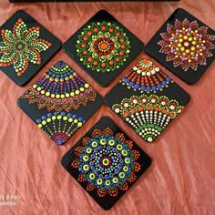 six coasters with colorful designs on them sitting on a pink cloth covered tablecloth