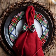 a red napkin with a bow sits on top of a black and white dinner plate