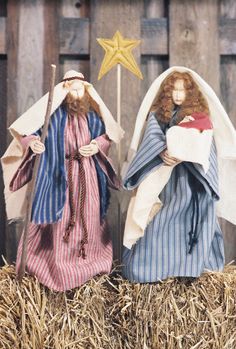 two nativity figurines sitting on top of hay