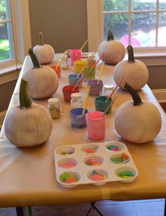 the table is set up with pumpkins and paint