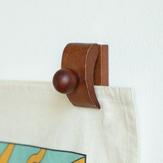 a wooden hook on the side of a white wall hanging from a canvas tote bag