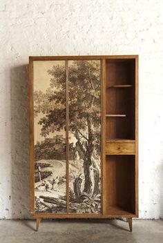 an old wooden cabinet with a painting on the door and shelves in front of it