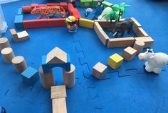 toys are arranged in the shape of animals and blocks on blue carpeted flooring