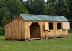 a wooden shed with two stalls on the grass