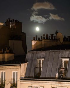 the full moon is setting over some rooftops