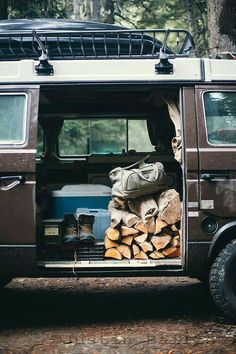 an old van is loaded with wood in the woods