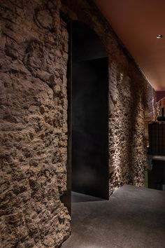 an open door leading into a room with stone walls and floor to ceiling lighting on either side