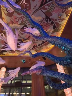 the ceiling is decorated with blue and white feathers hanging from it's sides, along with chandeliers