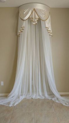 a white drape hanging from the ceiling in a room with beige walls and tile flooring