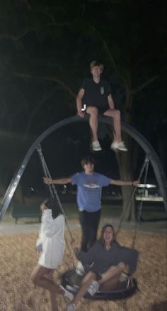 four people are hanging upside down in the air on swings at an amusement park or playground