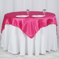 two empty plates are sitting on top of a pink and white tablecloth that has been draped over it