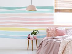 a bedroom with pink, blue and yellow stripes on the wall next to a bed