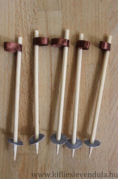 four wooden spoons are lined up in a row on a wood surface with brown ribbon