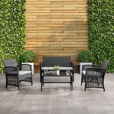 an outdoor living area with black wicker furniture and green plants on the wall behind it