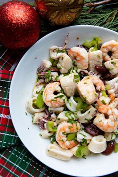 a white bowl filled with shrimp and vegetables next to a christmas ornament on a table