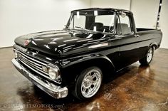 an old black pickup truck parked in a garage