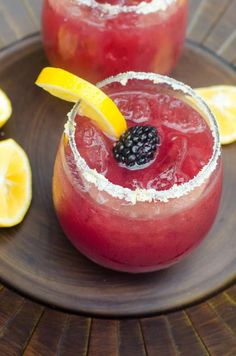 two glasses filled with fruit and garnish sit on a plate