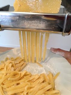 pasta being grated with cheese on top of a white plate in front of a person's hand