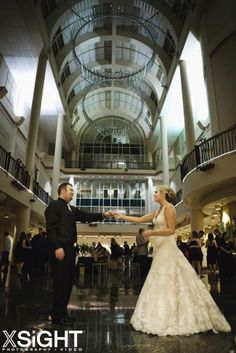 a bride and groom dancing in the middle of an atrium at their wedding reception,