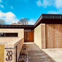 the entrance to a modern home with wood slats on the doors and brick walls