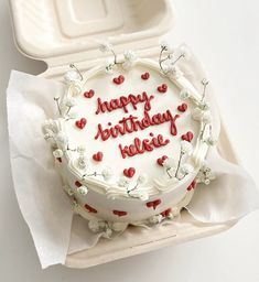 a birthday cake with white frosting and red writing on it sitting in a box