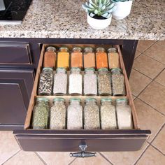 an open drawer filled with spices next to a potted plant