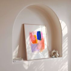 an abstract painting hangs on the wall next to a shelf