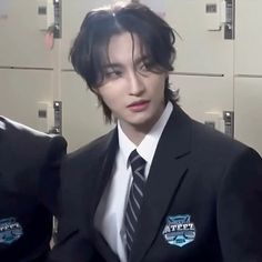 a man in a suit and tie standing next to lockers with badges on them