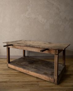 an old wooden table sitting on top of a hard wood floor next to a wall