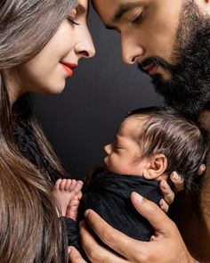 a man and woman holding a baby in their arms