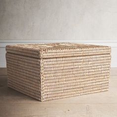 a wicker box sitting on top of a wooden floor next to a white wall