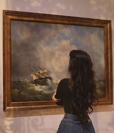 a woman looking at a painting on the wall